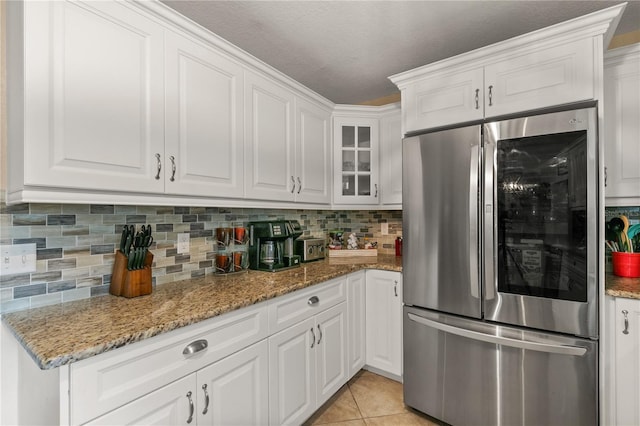 kitchen with light tile patterned floors, smart refrigerator, white cabinetry, and backsplash