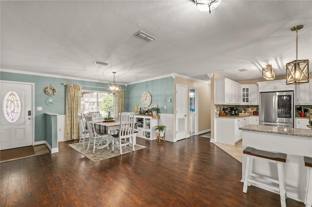 dining area with ornamental molding, wood finished floors, and visible vents