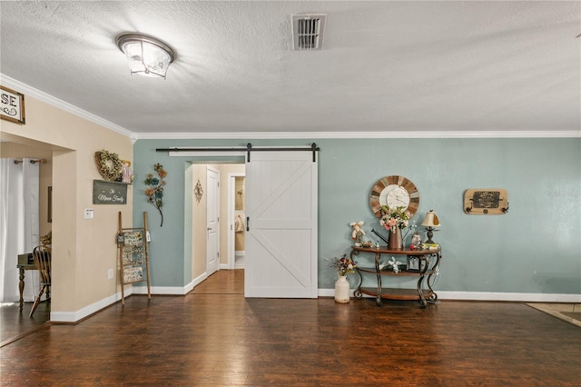 foyer featuring visible vents, a barn door, ornamental molding, wood finished floors, and baseboards