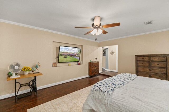 bedroom with baseboards, crown molding, visible vents, and wood finished floors