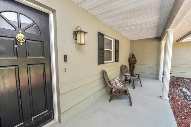 entrance to property with covered porch and stucco siding