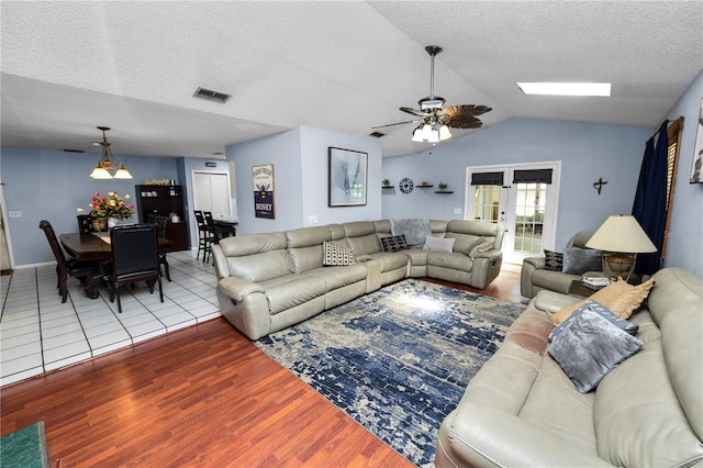 living area featuring french doors, lofted ceiling, visible vents, a textured ceiling, and wood finished floors