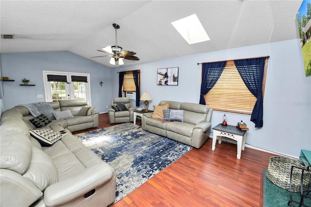 living room featuring visible vents, lofted ceiling with skylight, a ceiling fan, a textured ceiling, and wood finished floors