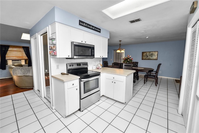 kitchen featuring visible vents, a peninsula, stainless steel appliances, light countertops, and light tile patterned flooring