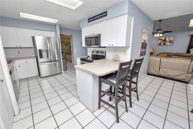 kitchen featuring light tile patterned floors, stainless steel appliances, light countertops, open floor plan, and a peninsula