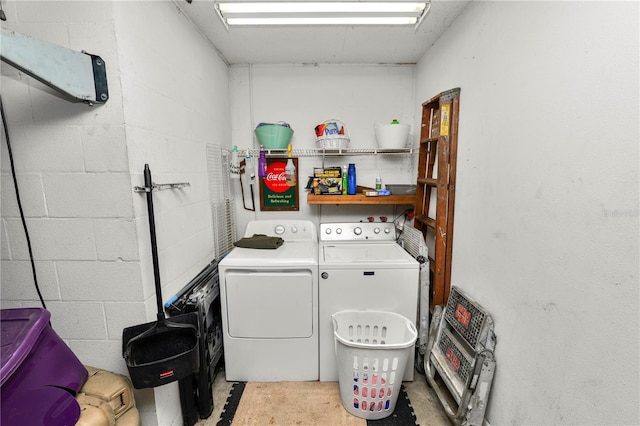 laundry area with laundry area, washing machine and dryer, and concrete block wall