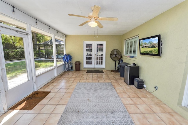 unfurnished sunroom featuring french doors, rail lighting, and ceiling fan