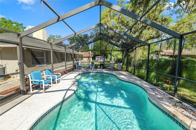 outdoor pool with glass enclosure, a patio, and central AC unit