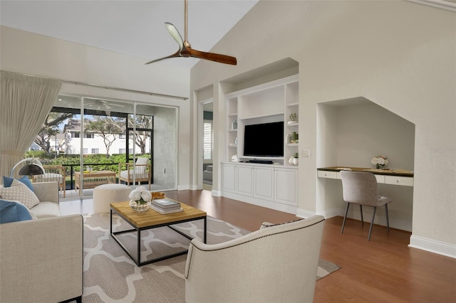 living room featuring built in features, built in desk, ceiling fan, wood finished floors, and high vaulted ceiling