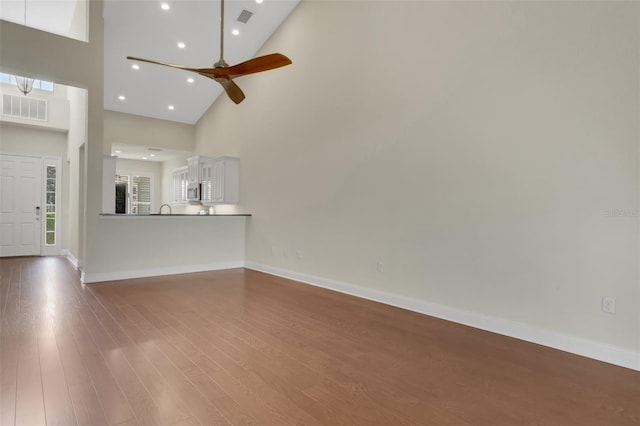 unfurnished living room with baseboards, visible vents, and wood finished floors