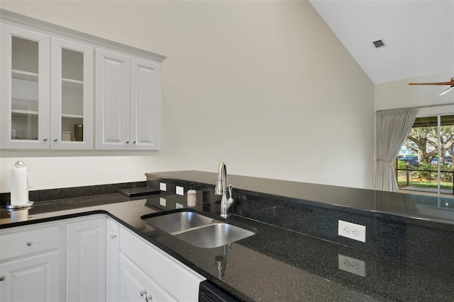 kitchen featuring lofted ceiling, visible vents, glass insert cabinets, white cabinetry, and a sink