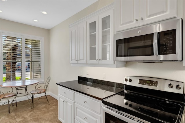 kitchen featuring dark countertops, white cabinets, stainless steel appliances, and glass insert cabinets