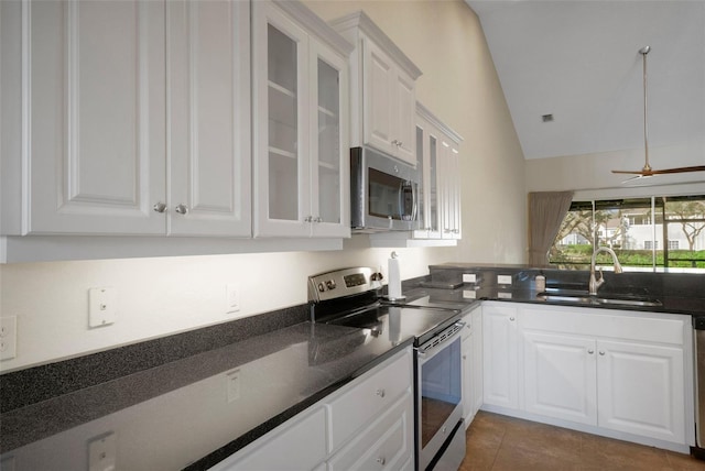 kitchen featuring lofted ceiling, a sink, white cabinets, appliances with stainless steel finishes, and glass insert cabinets