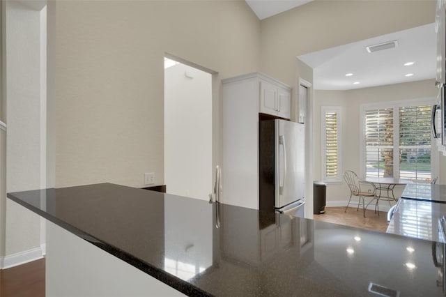 kitchen with dark countertops, baseboards, white cabinetry, and freestanding refrigerator