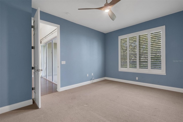 carpeted empty room featuring ceiling fan and baseboards