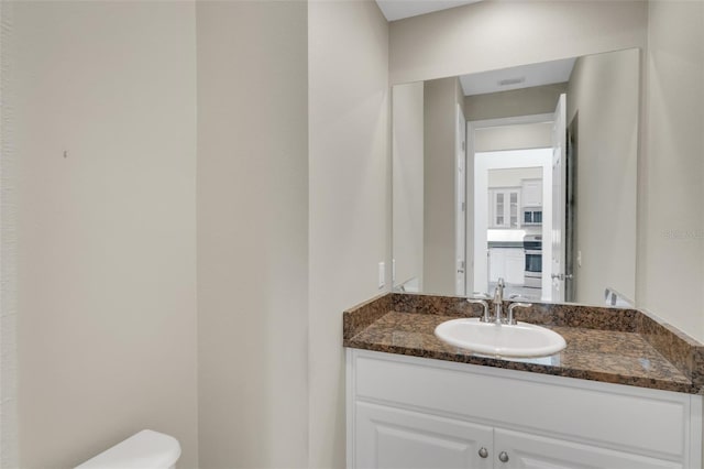 half bath featuring visible vents, vanity, and toilet