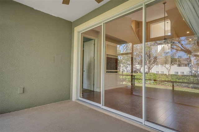 interior space featuring carpet floors, a textured wall, and ceiling fan