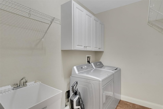 laundry room featuring light tile patterned floors, a sink, baseboards, cabinet space, and washer and clothes dryer