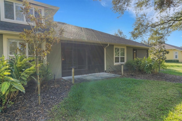 rear view of property with a sunroom, roof with shingles, a yard, and stucco siding