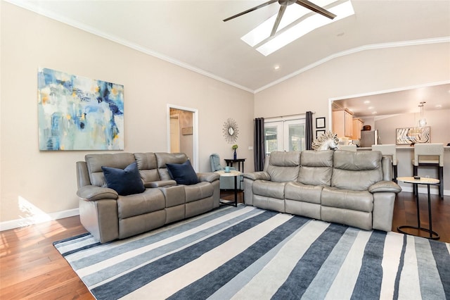 living area featuring vaulted ceiling with skylight, baseboards, crown molding, and wood finished floors