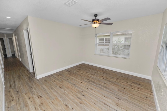 unfurnished room featuring a ceiling fan, visible vents, baseboards, and wood finished floors