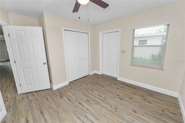 unfurnished bedroom featuring a ceiling fan, a closet, light wood-style flooring, and baseboards