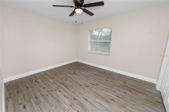 empty room with ceiling fan, baseboards, and wood finished floors