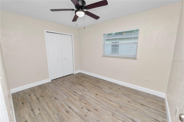 unfurnished bedroom featuring ceiling fan, a closet, wood finished floors, and baseboards