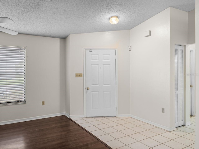 foyer with light wood-type flooring, a textured ceiling, and baseboards