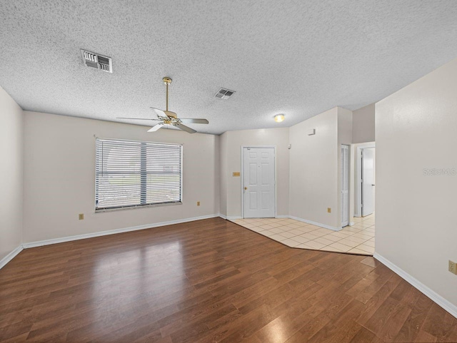 unfurnished room with a ceiling fan, visible vents, a textured ceiling, and wood finished floors