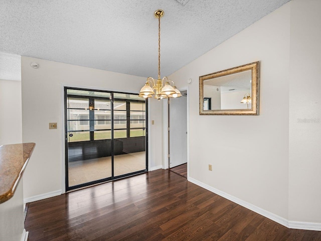 unfurnished dining area with a chandelier, vaulted ceiling, a textured ceiling, and wood finished floors