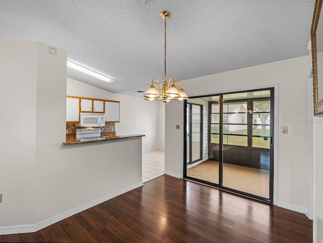 interior space with baseboards, dark wood finished floors, lofted ceiling, a textured ceiling, and a notable chandelier