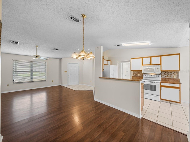 kitchen featuring light wood-style floors, white appliances, visible vents, and vaulted ceiling