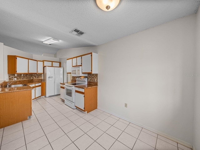 kitchen featuring light tile patterned floors, white appliances, a sink, visible vents, and backsplash