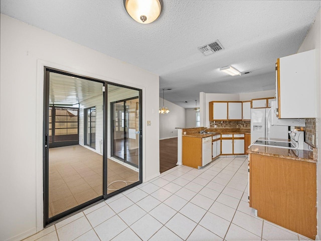 kitchen with light tile patterned floors, white appliances, a sink, visible vents, and white cabinets