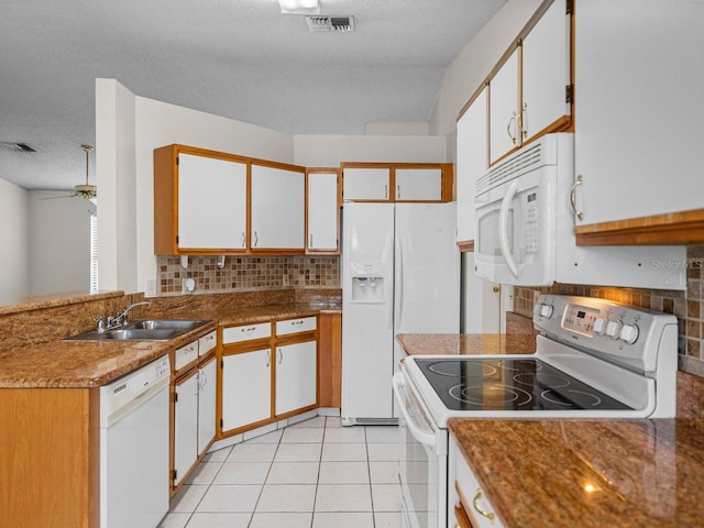 kitchen with white appliances, light tile patterned floors, visible vents, and a sink