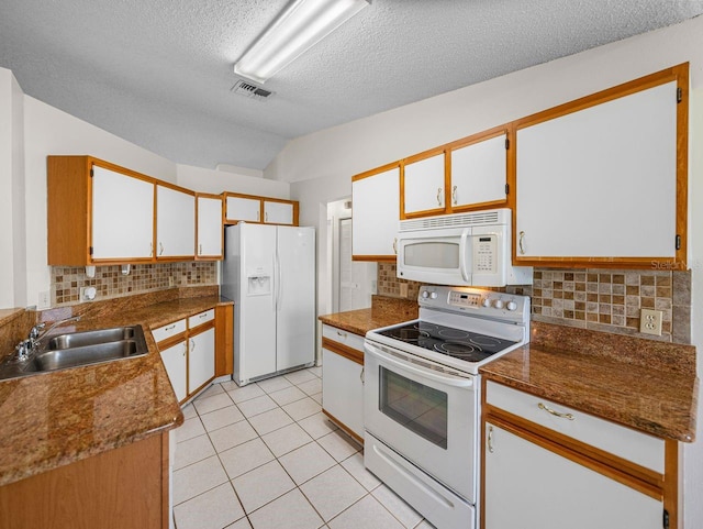 kitchen featuring light tile patterned floors, tasteful backsplash, visible vents, a sink, and white appliances