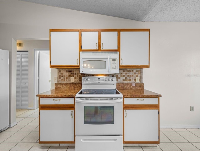 kitchen featuring light tile patterned floors, lofted ceiling, decorative backsplash, white cabinetry, and white appliances