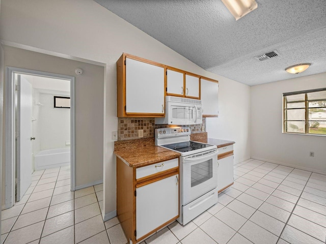 kitchen featuring light tile patterned floors, lofted ceiling, white appliances, visible vents, and tasteful backsplash