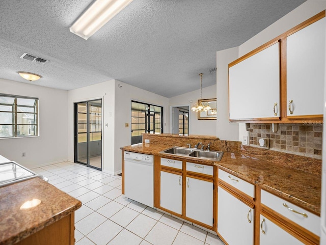 kitchen with light tile patterned floors, decorative backsplash, a sink, dishwasher, and a peninsula