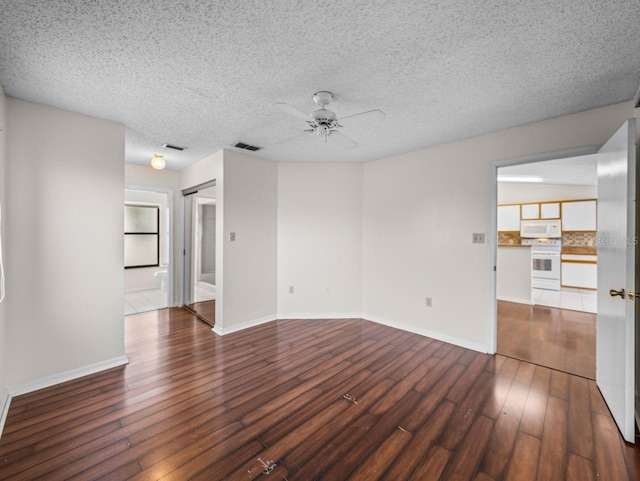 spare room with ceiling fan, wood-type flooring, visible vents, and baseboards