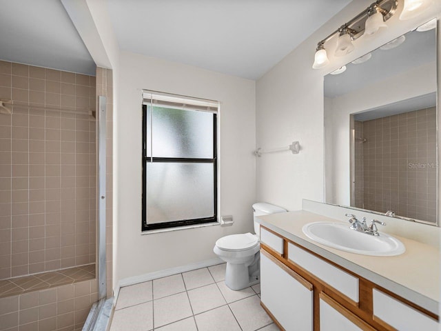 full bath with toilet, a tile shower, vanity, tile patterned flooring, and baseboards