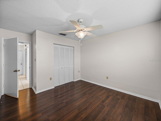 unfurnished bedroom featuring baseboards, a closet, visible vents, and wood finished floors