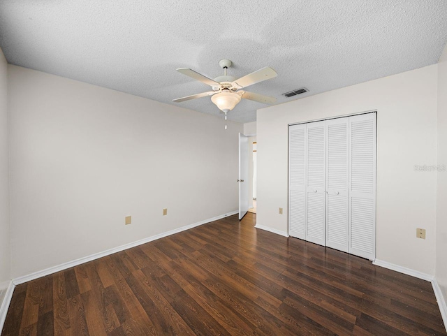 unfurnished bedroom with a closet, visible vents, a textured ceiling, wood finished floors, and baseboards