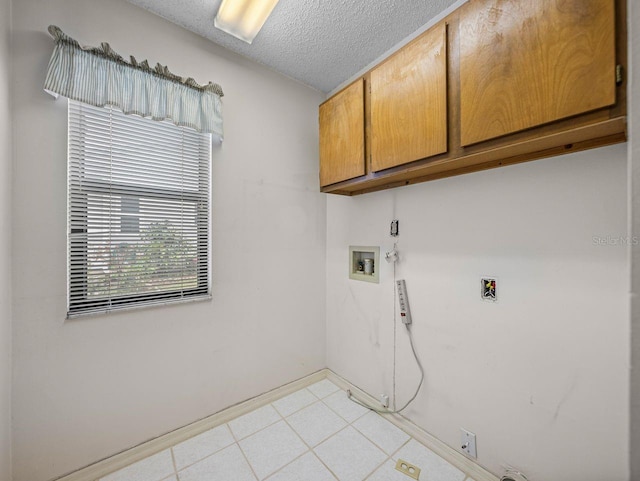 clothes washing area with washer hookup, cabinet space, light tile patterned flooring, a textured ceiling, and baseboards