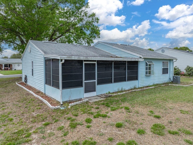 rear view of property with a sunroom, a lawn, and roof with shingles