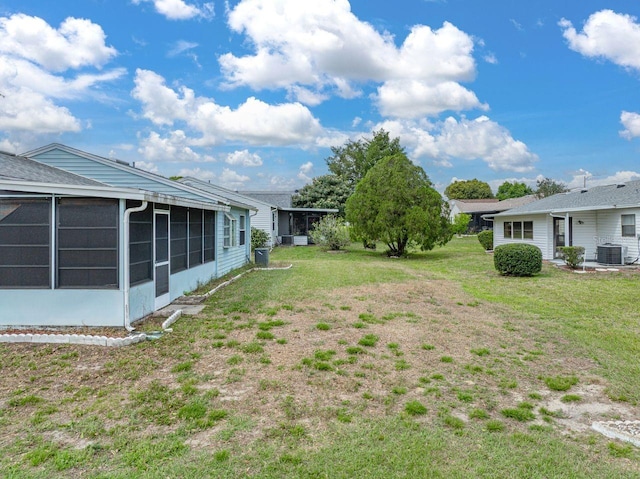 view of yard featuring a sunroom and central AC