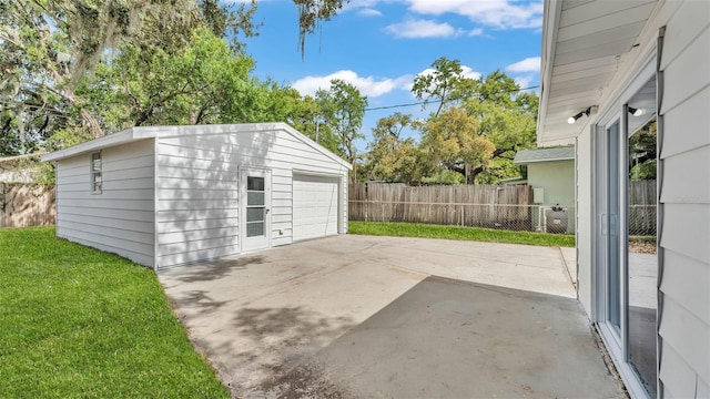 detached garage featuring driveway and fence