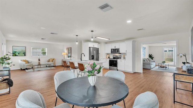 dining space featuring light wood-style floors and visible vents