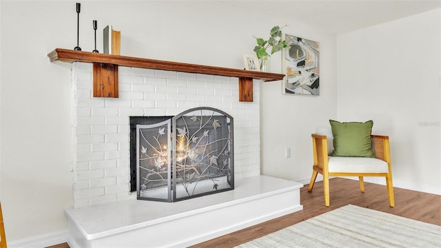 details featuring a brick fireplace, baseboards, and wood finished floors